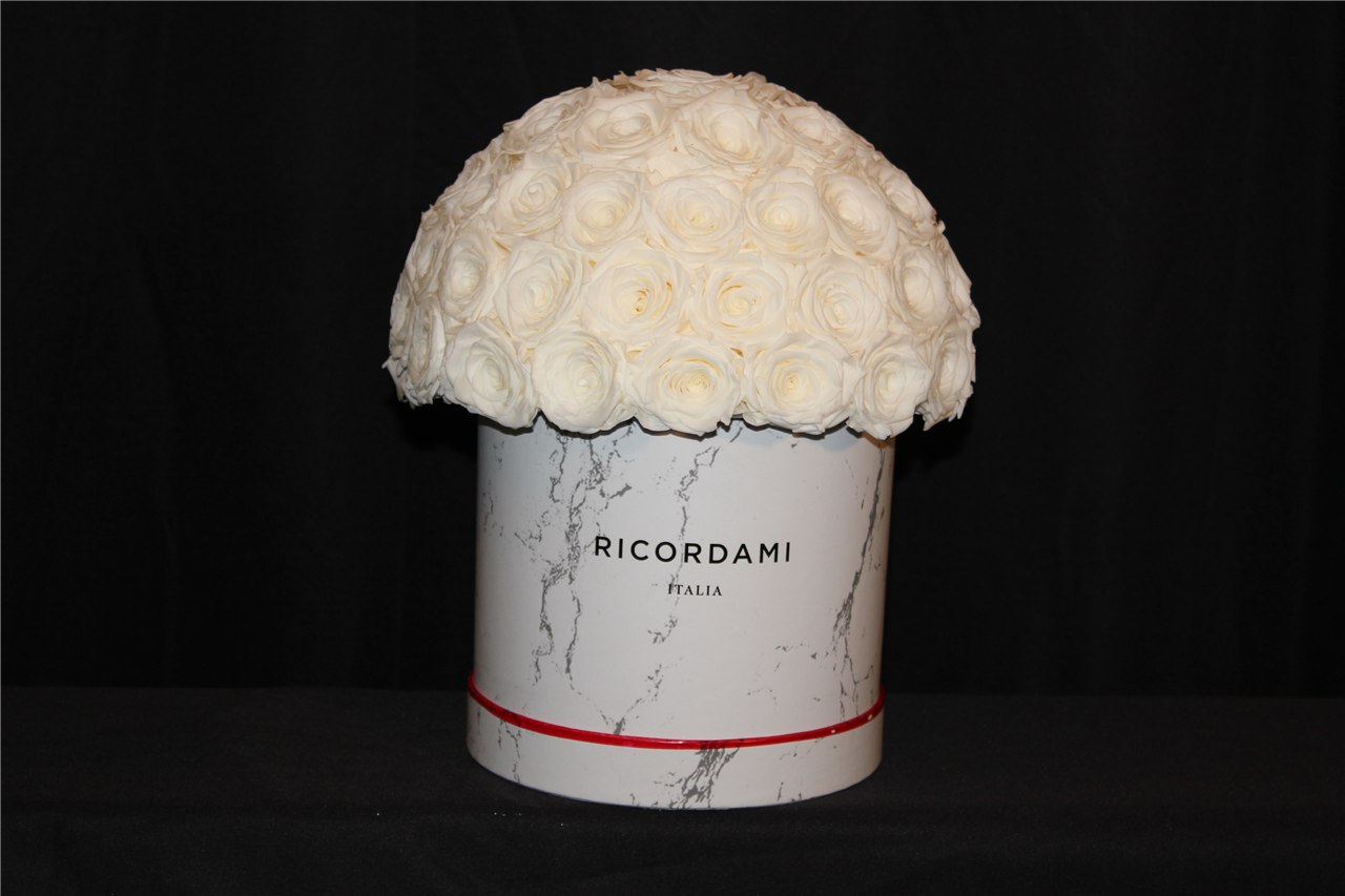 Real white rose arrangement in a white marble-look round container